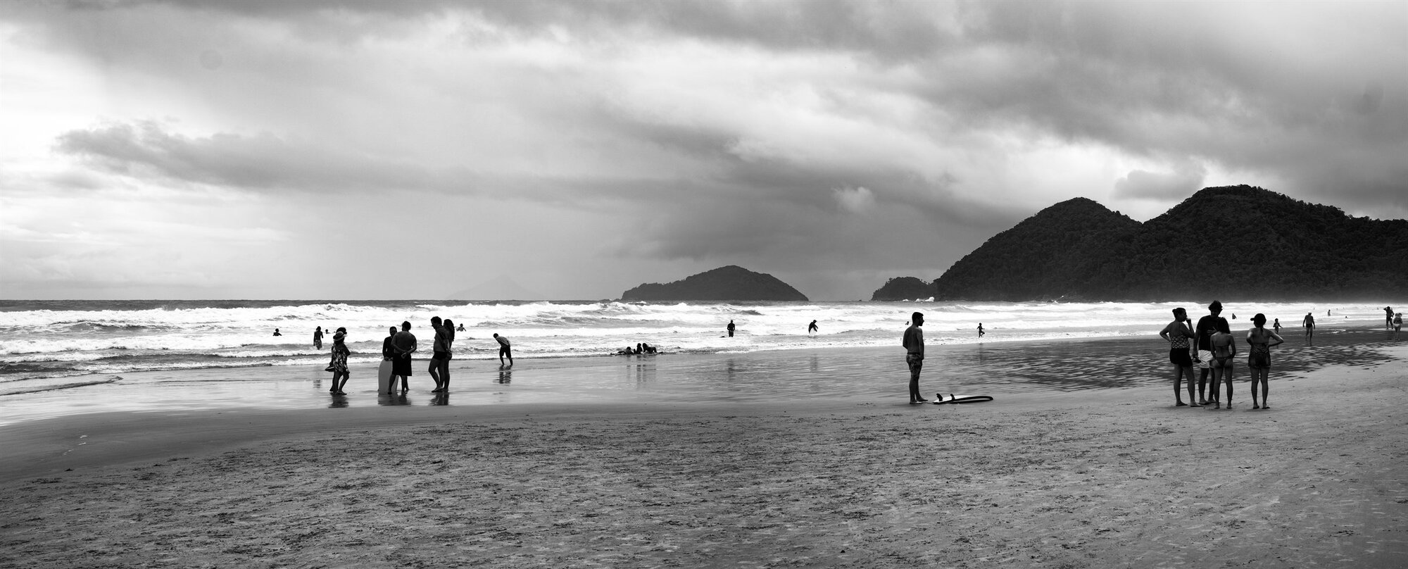 People on a wide beach below green hills