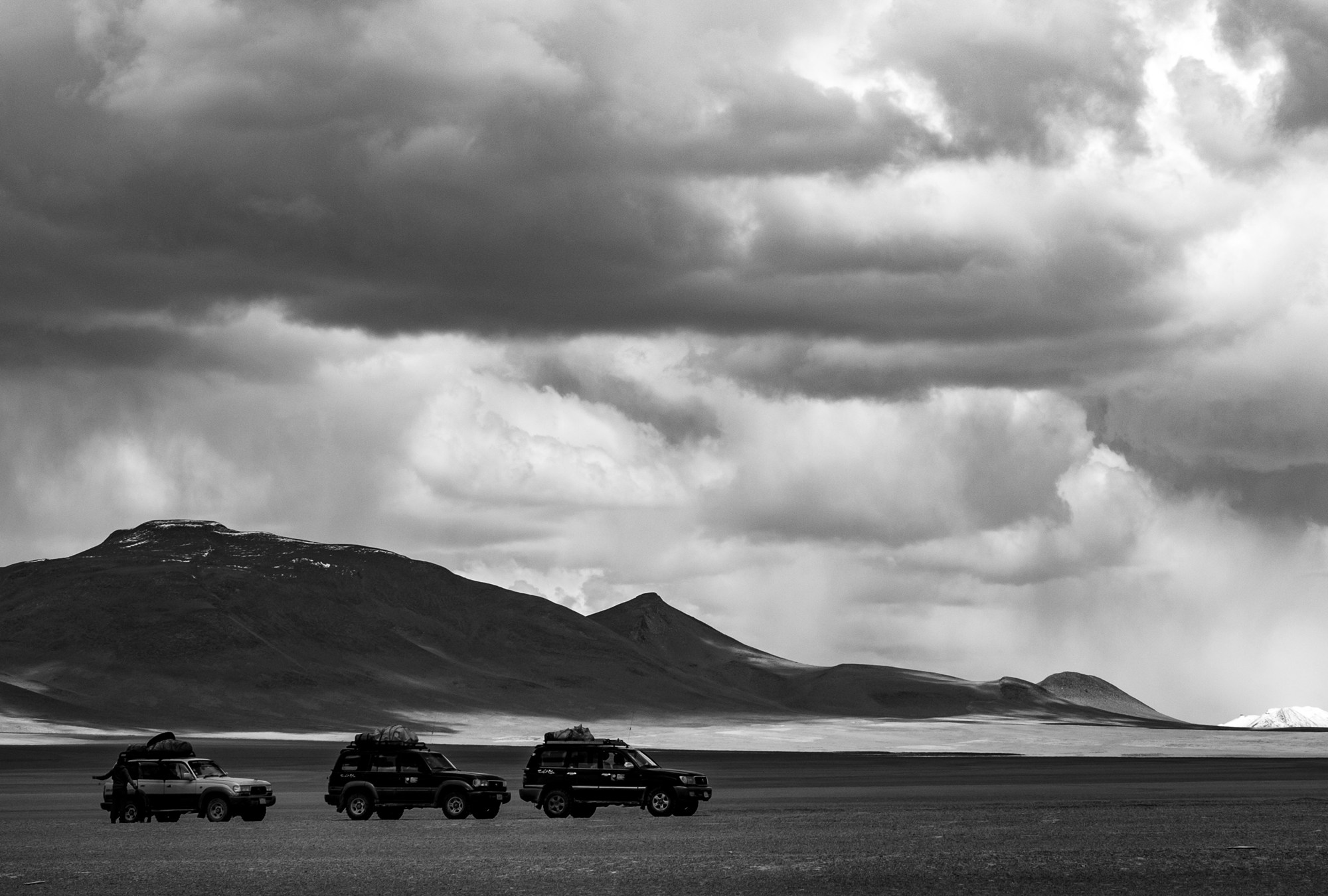 Three jeeps on a high plain beneath storm clouds